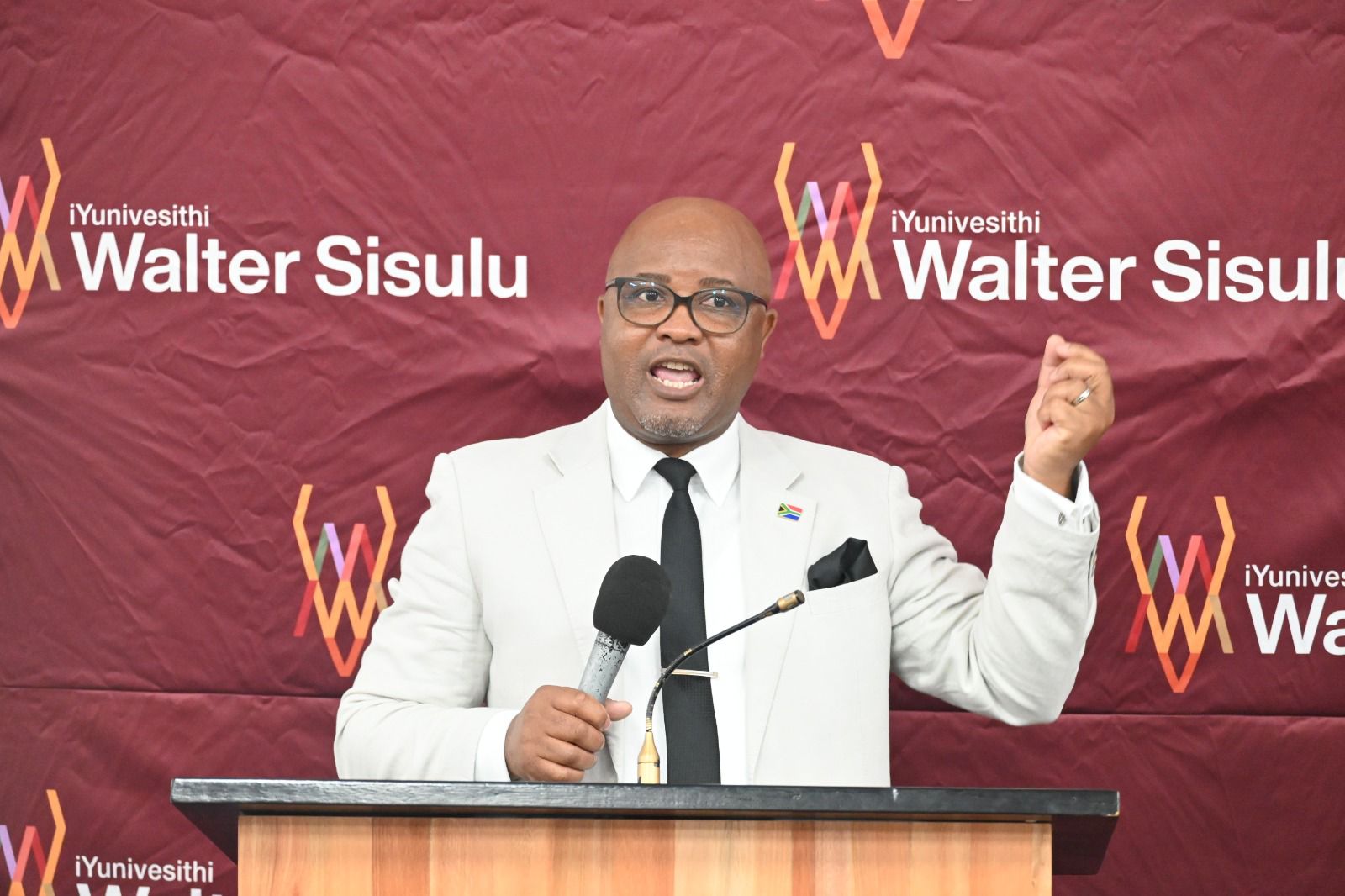 iYunivesithi Walter Sisulu Public Law researcher Zibele Nodangala speaking at a podium.